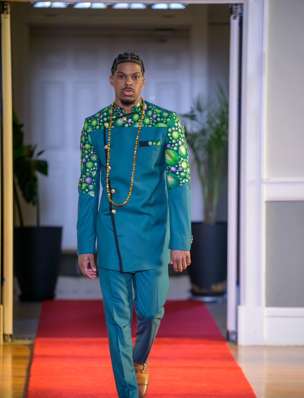 Adeyemi RoyaLabel menswear look, a deep teal tailored suit with patterned textile across the shoulders and gold buttons