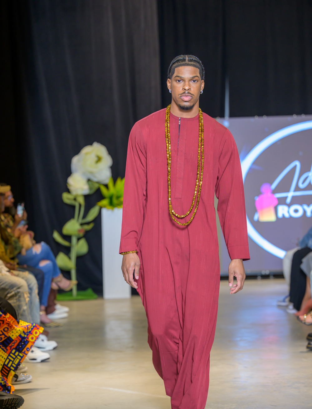Adeyemi Royalabel menswear look, a long burgundy garment worn with layered gold beaded strands