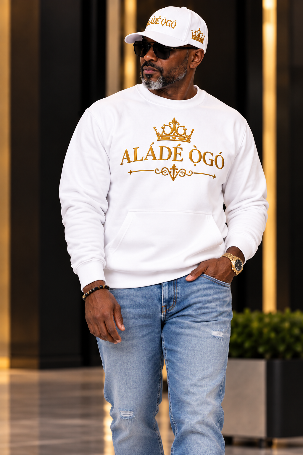 Man wearing the white ALÁDÉ ÒGÓ crewneck with denim and snapback